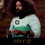 Image of Reggie Watts wearing a sweater with a robot space cat (or maybe a drone) on it, on Comedy Bang! Bang!